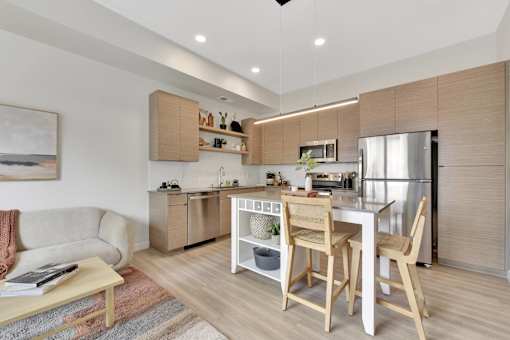 A modern kitchen with wooden chairs and a dining table.