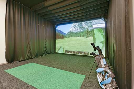 A golf simulator room with a screen showing a golf course.