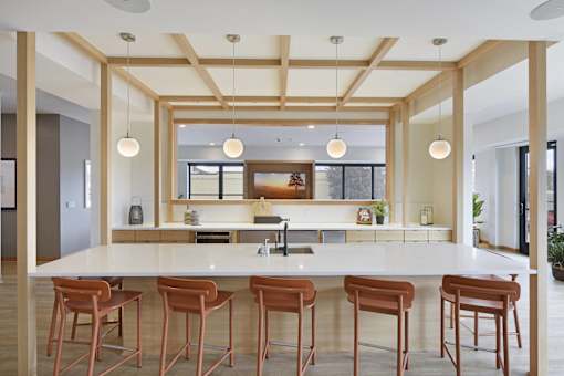 A kitchen with a white counter and brown stools.