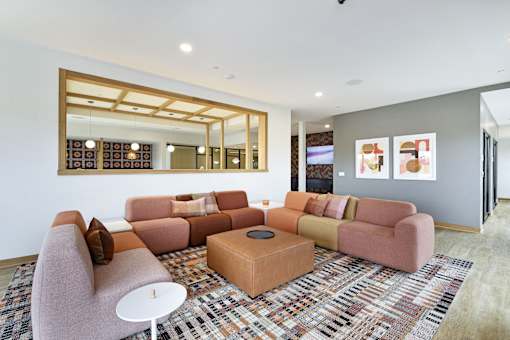 A living room with a pink couch, a white table, and a large mirror on the wall.