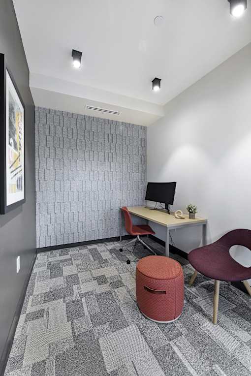 A small office with a desk, chair, and trash can.