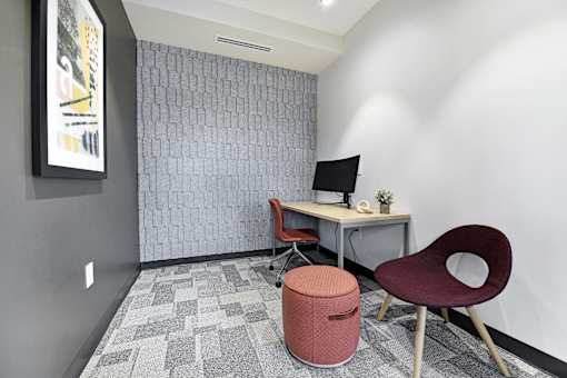 A room with a desk, chair, and a trash can.