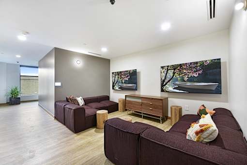 A living room with a brown couch and a painting on the wall.