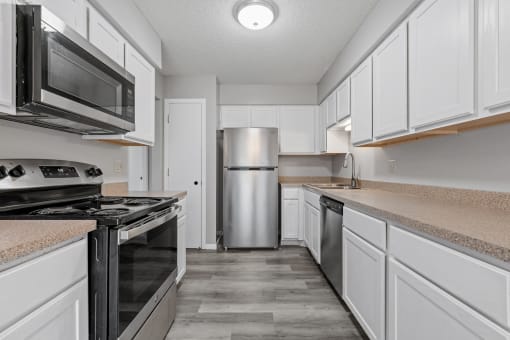 an empty kitchen with white cabinets and stainless steel appliances
