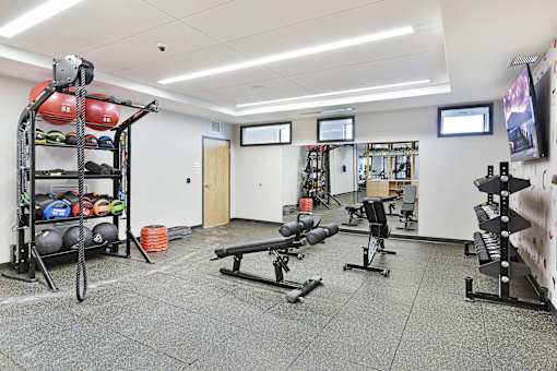 A gym with a variety of equipment including weights and benches.