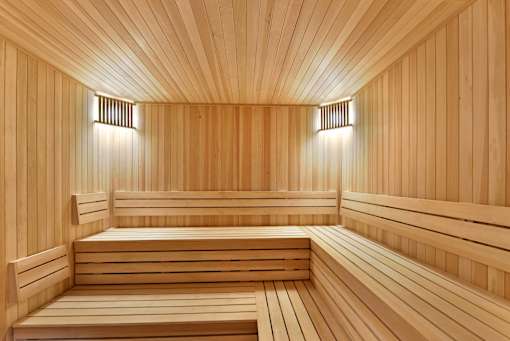 A wooden sauna with benches and lights on the wall.