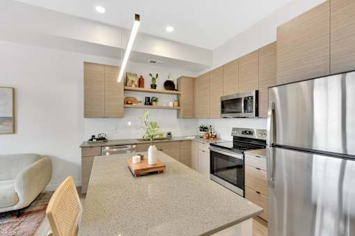 A modern kitchen with a stainless steel refrigerator, a wooden cutting board on the island, and a white chair.