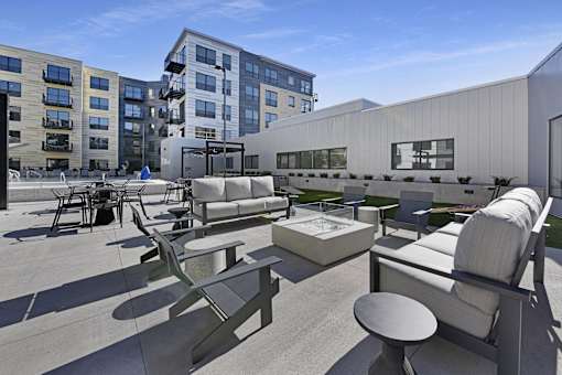 A modern outdoor seating area with concrete furniture and a white building in the background.