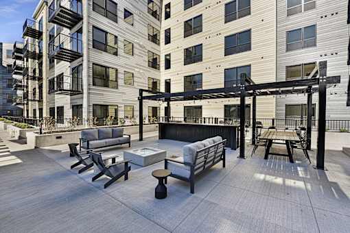A patio area with a table and chairs is surrounded by apartment buildings.