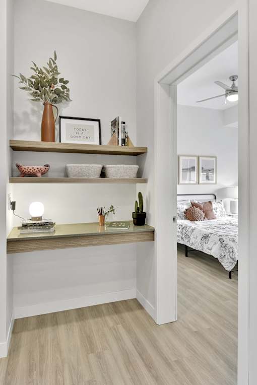 A bedroom with a bed, a shelf with decorative items, and a mirror.