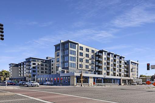A modern multi-story building with a parking lot in front.