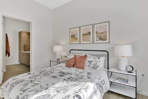 A bedroom with a large bed and a nightstand with a lamp on it.