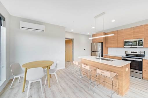 A modern kitchen with a wooden table and white chairs.