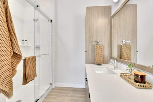 A bathroom with a white sink and a brown towel hanging on the shower rod.