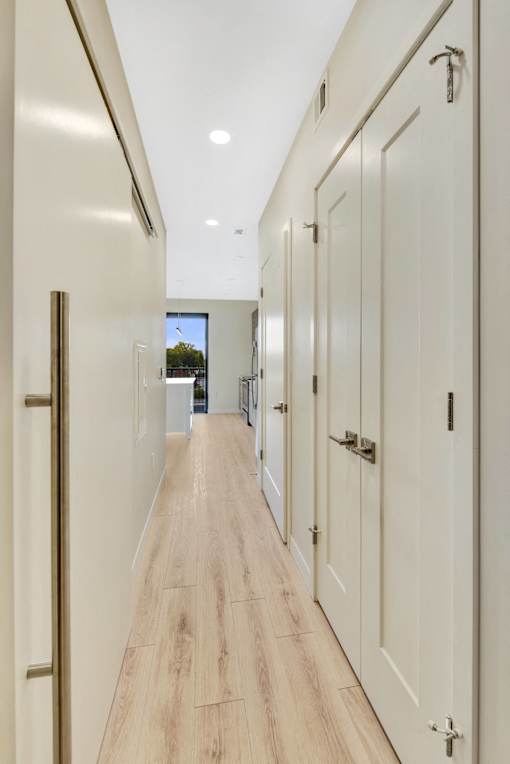 A long hallway with white doors and wood floors.