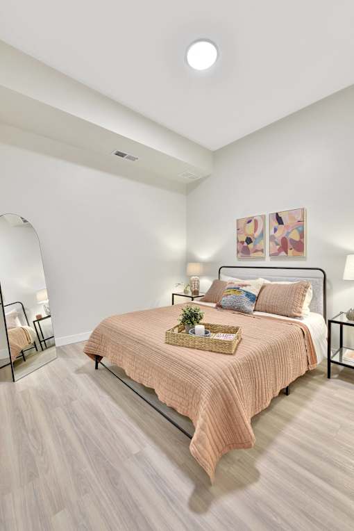 A bedroom with a bed, nightstand, and a painting on the wall.