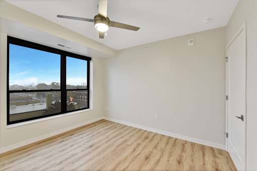 A room with a ceiling fan and a large window overlooking a cityscape.