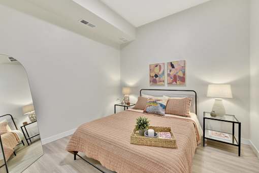 A bedroom with a bed, nightstand, and two wall lamps.