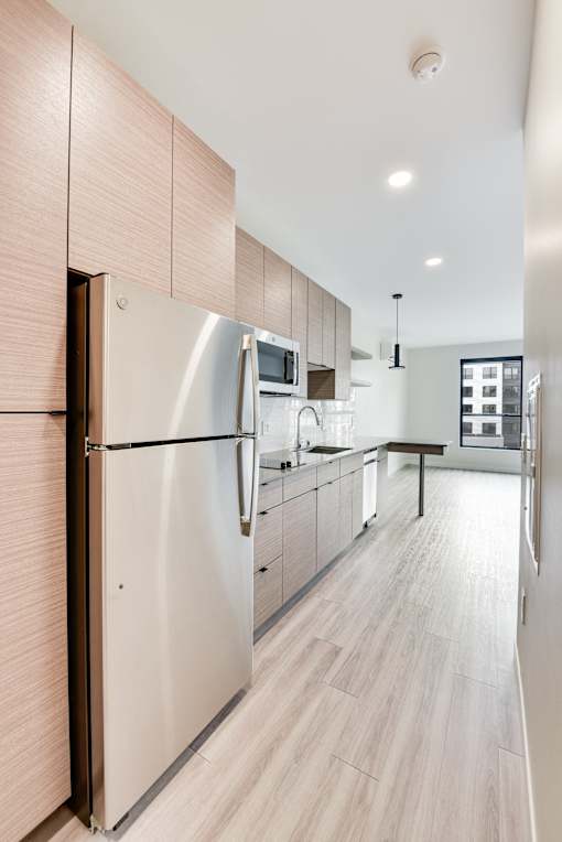A modern kitchen with a stainless steel refrigerator and wooden cabinets.