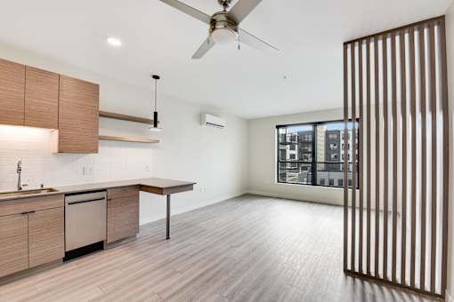 A modern kitchen with wooden cabinets and a ceiling fan.