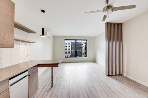 A modern kitchen with a wooden floor and a ceiling fan.