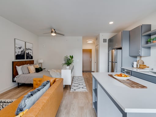 a living room with a yellow couch and a kitchen with a sink