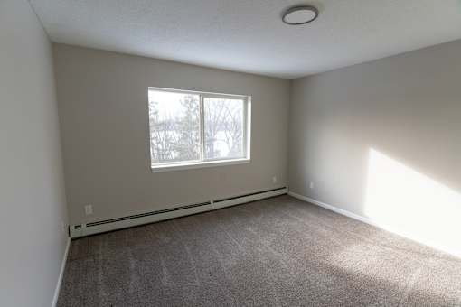 A room with a window and carpeted floor.