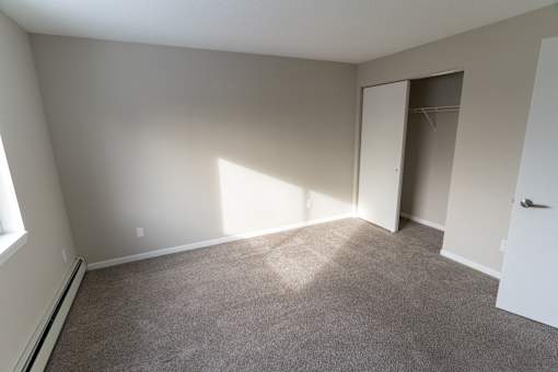 A room with a carpeted floor and a door leading to another room.