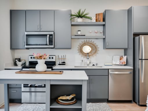 a kitchen with gray cabinets and stainless steel appliances and a white counter top