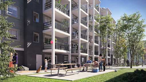 A group of people are gathered on a patio in front of a building with balconies.