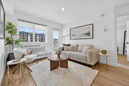 A living room with a white couch, a coffee table, and a large window.