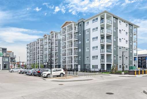 A large apartment complex with a parking lot in front.