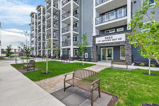 A bench is situated on a concrete walkway in front of a building.