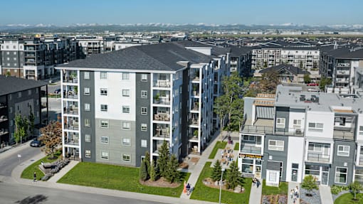 Apartment buildings with green lawns and trees in front.