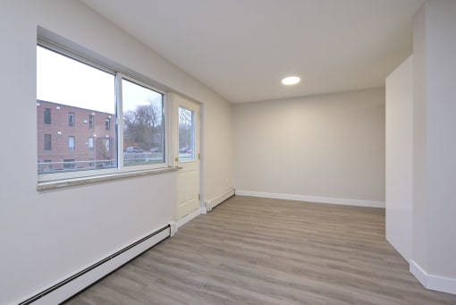 a bedroom with a large window and hardwood floors