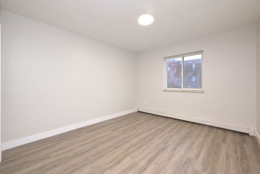 a bedroom with hardwood floors and white walls