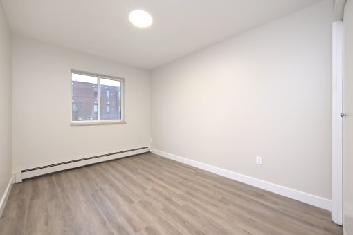 a bedroom with hardwood floors and white walls