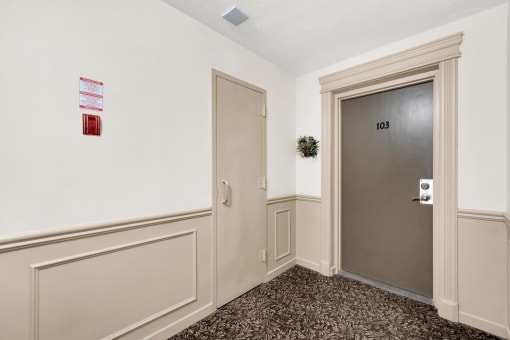 a hallway with a gray door and a carpeted floor