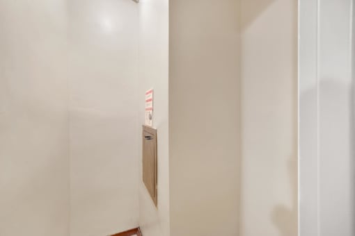 a small door in the wall of a room with white walls and a wooden floor