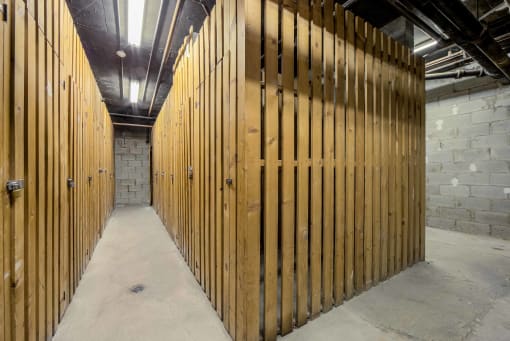 a large wooden gate in a room with concrete floors and a brick wall