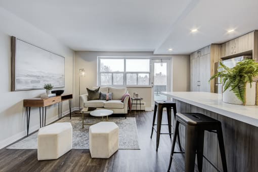 a living area with a couch a table with stools and a counter top with a bar
