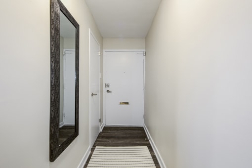 a hallway with white walls and a large mirror on the wall