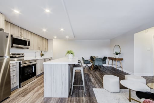 a kitchen and living room with white walls and wood flooring