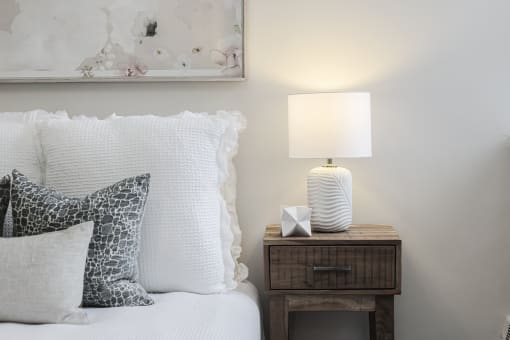 a bedroom with a bed with white bedding and a nightstand with a lamp and a