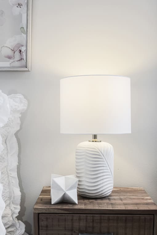 a lamp on a nightstand with a white lampshade