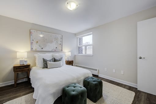 a bedroom with a large white bed and a green ottoman at the end of the