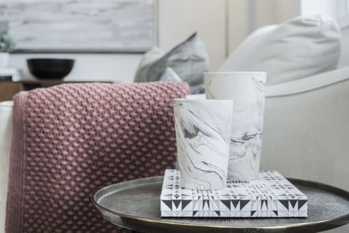 a living room with a sofa and a coffee table with two white vases on top of