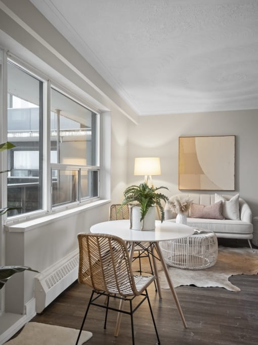 a living room with a round white table and three rattan chairs