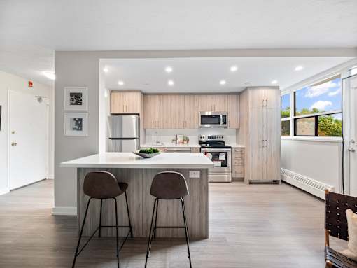 A modern kitchen with a bar area and two chairs.