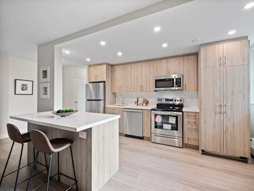 A modern kitchen with a white island and wooden cabinets.